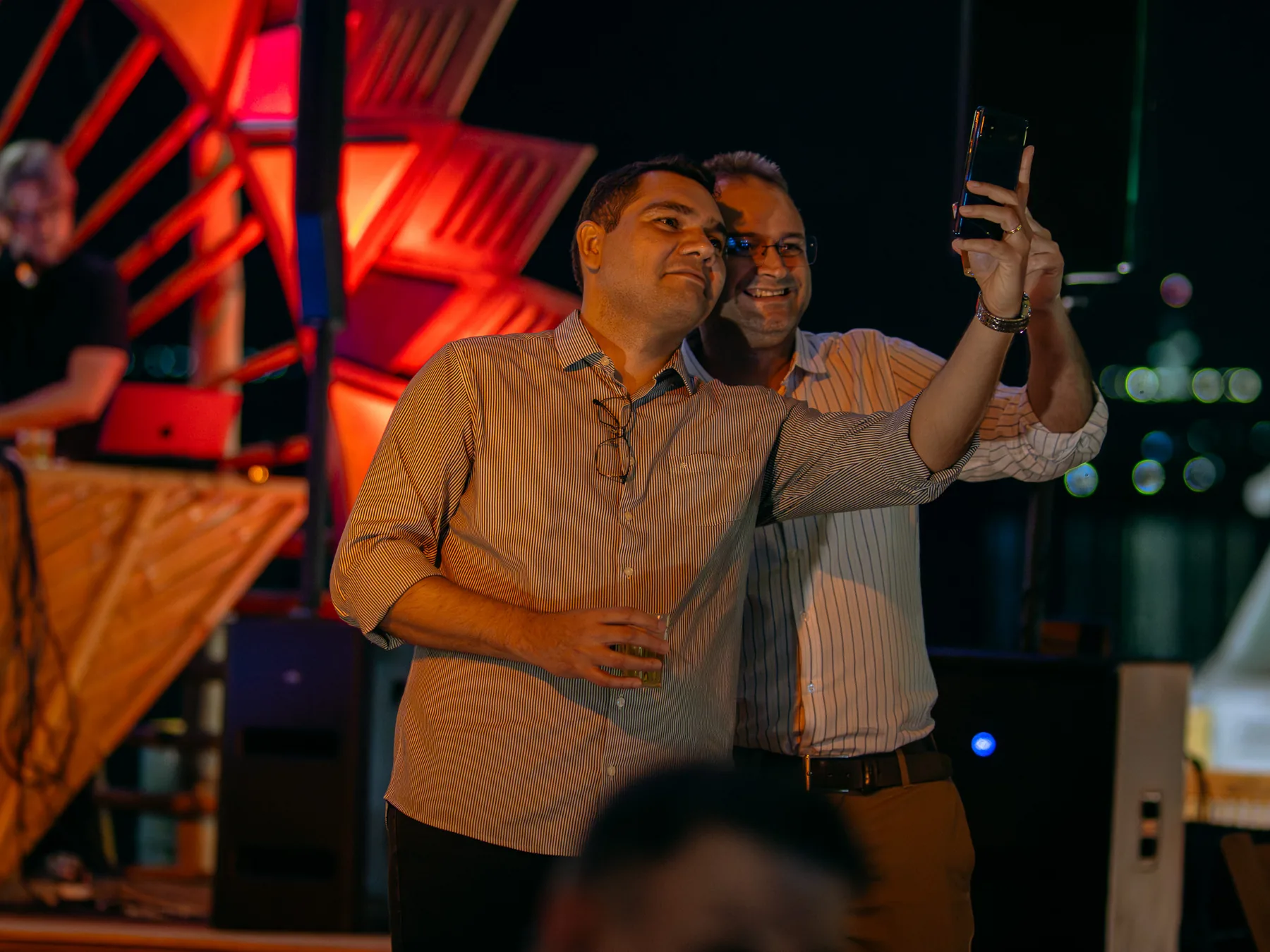 Colegas fazendo selfie no palco iluminado durante evento de empresa