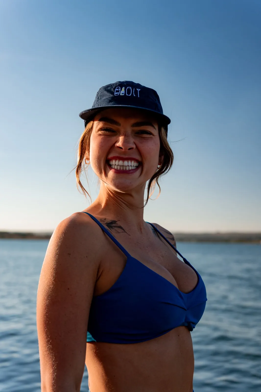 Mulher rindo sobre a água dourada do Lago Paranoá