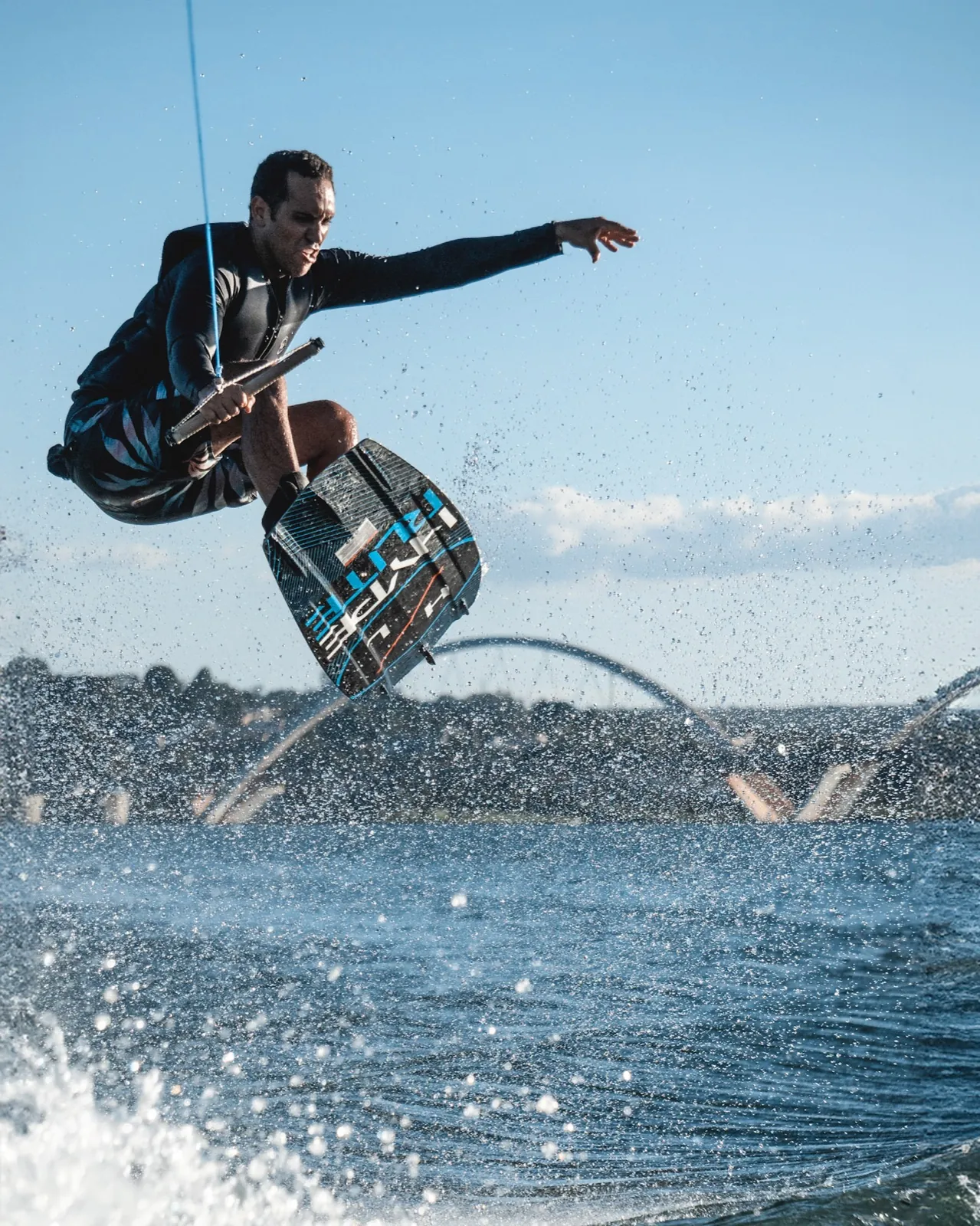 Manobra de wakeboard com os jatos da ponte ao fundo